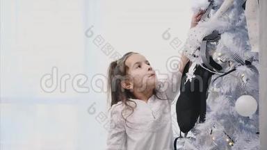 小女孩正在家里装饰一棵圣诞树，上面有蝴蝶结、蝴蝶结和袜子。